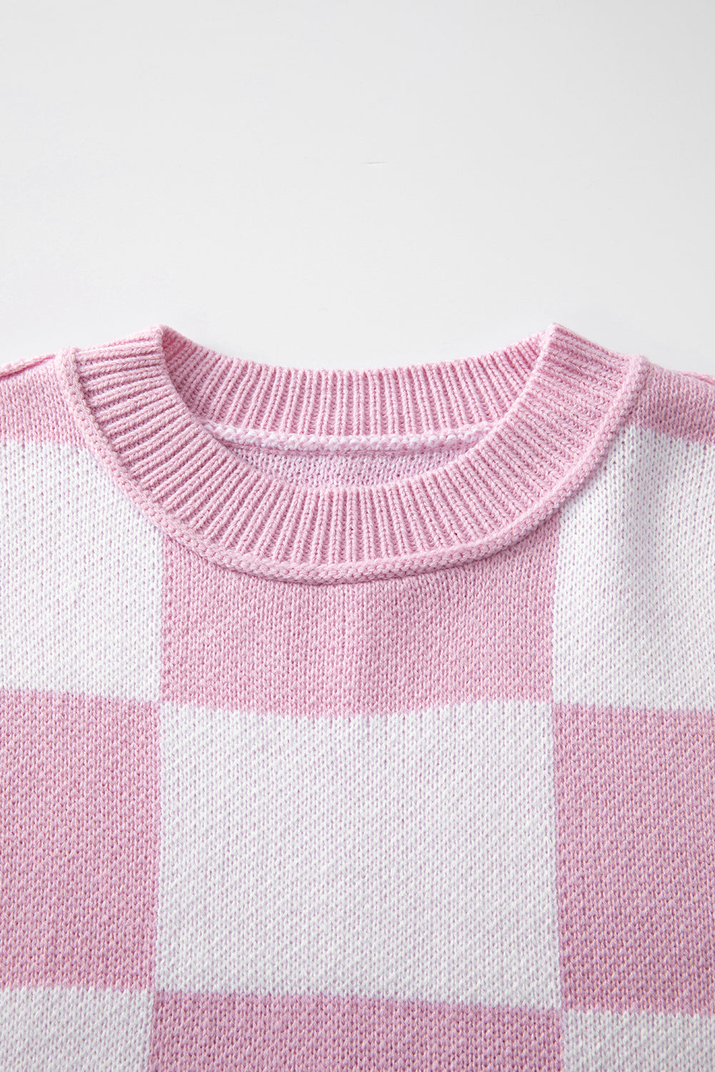 Close-up of a pink and white checkered bishop sleeve sweater neckline.